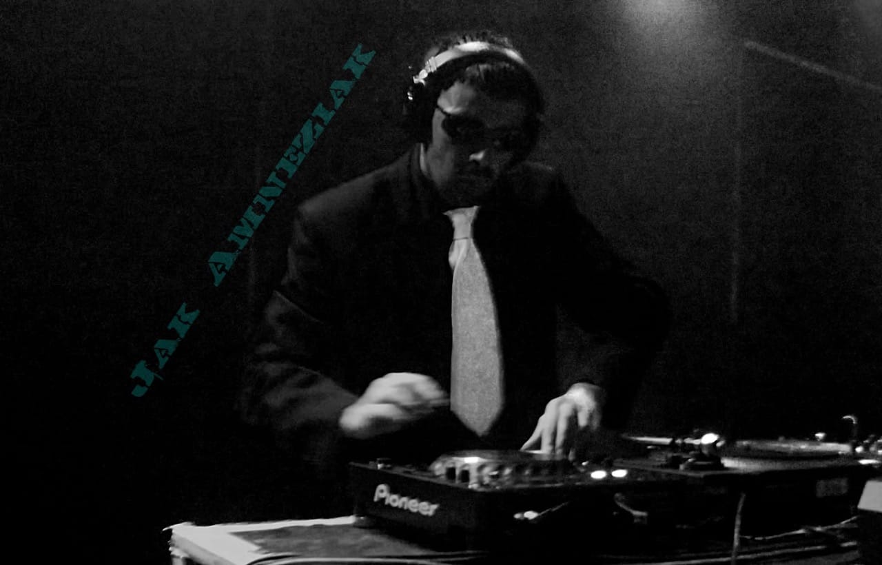 Jak Amneziak at a pair of turntables, in black and white