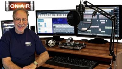 Matt Craig at his radio desk in front of studio monitors, with an On Air sign lit above