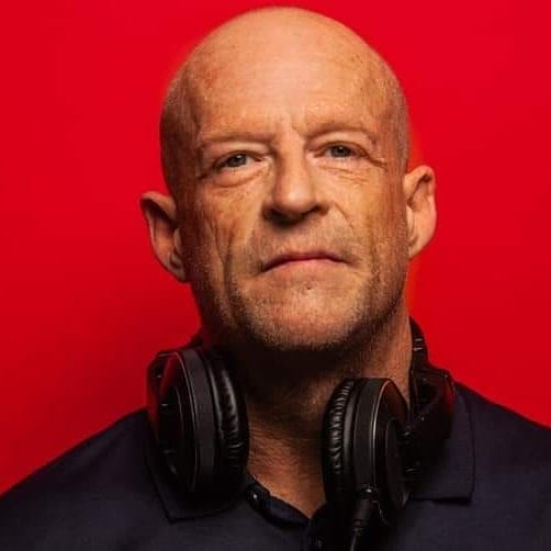 WayneDjc with headphones around his neck against a red background